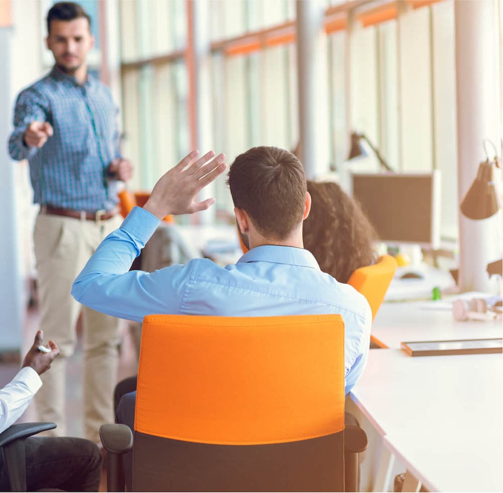 Man raising his hand in an HR team meeting held in a modern office.
